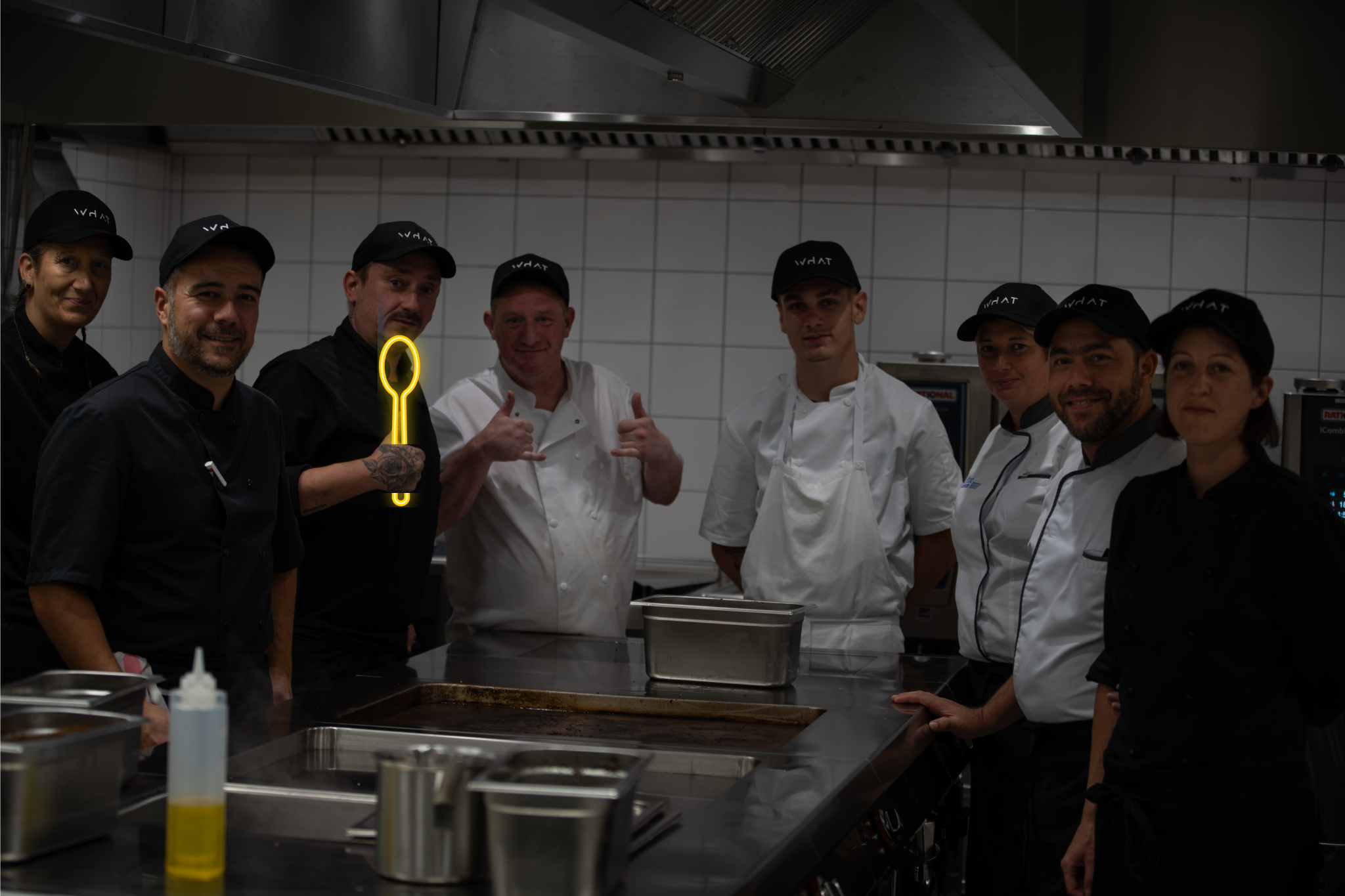 les équipes de la cuisine du WHAT avec le chef Manu. Ils ont leurs tenues de travaillent avec leurs casquettes WHAT et leurs tabliers